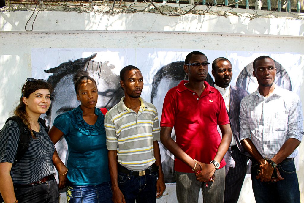 Fellow advocates pose in front of cholera victims' images at the UN log base in Port-au-Prince. Photo credit: Ted Oswald.