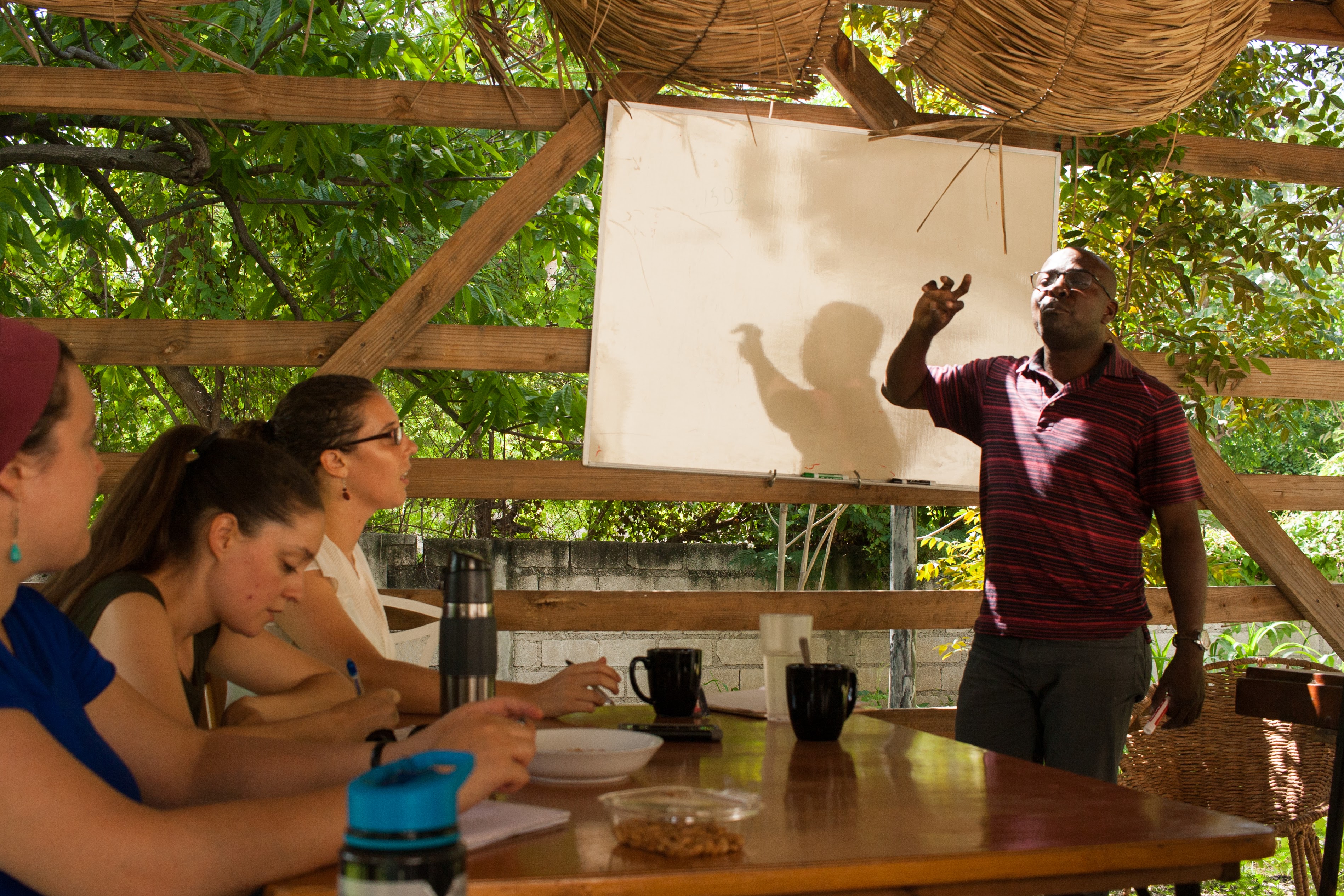 Nixon Boumba (right) teaches on Haitian history at the MCC Haiti office. Anna Vogt 